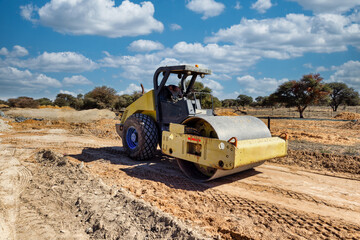 compactor heavy machinery paving a dirt road on a construction site