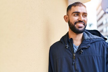 Young hispanic man smiling confident looking to the side at street