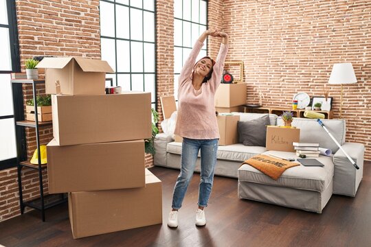 Young caucasian woman smiling confident stretching arms at new home