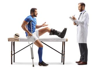 Football player with a leg injury talking to a male doctor