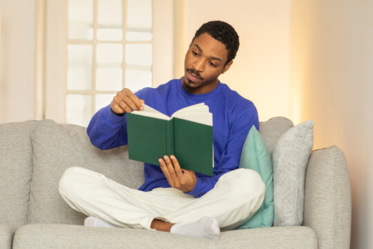 Black guy in casual reading book for pleasure at home