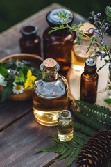 Natural organic essential oil in small glass bottles on wooden background. Homemade production for spa, sauna, bath. Relaxation, alternative medicine, remedy, naturopathy, pure ingredients