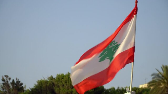 Flag of Lebanon waves in the wind, blue sky is in the background.