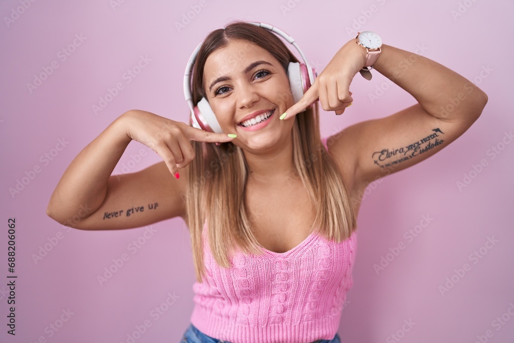 Canvas Prints young blonde woman listening to music using headphones smiling cheerful showing and pointing with fi