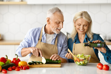 Joyful elderly couple enjoying cooking together in home kitchen
