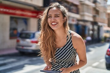 Young beautiful hispanic woman smiling confident using touchpad at street