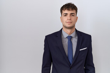 Young hispanic business man wearing suit and tie relaxed with serious expression on face. simple and natural looking at the camera.