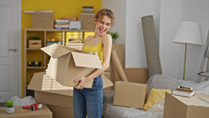Fototapeta na wymiar Young woman holding package smiling at new home