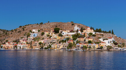 Fototapeta na wymiar Multi-colored facades of houses in the village Symi on a sunny day.