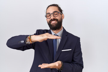 Hispanic man with beard wearing suit and tie gesturing with hands showing big and large size sign, measure symbol. smiling looking at the camera. measuring concept.