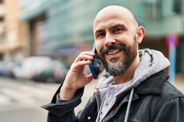 Young bald man smiling confident talking on the smartphone at street