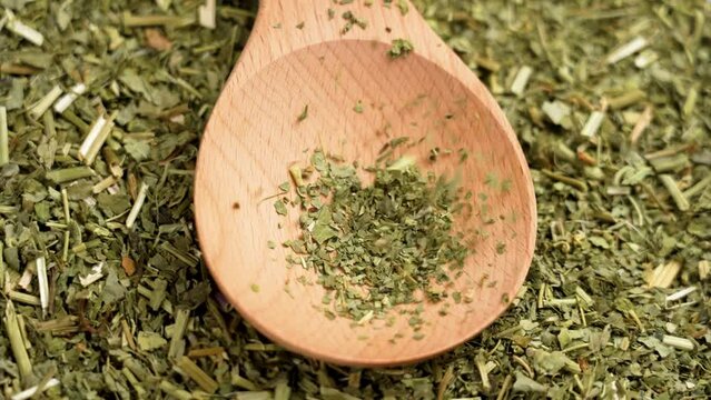 Passion flower dried herbs. Dry Passiflora incarnata. Alternative herbal medicine green ingredient falling on a wooden spoon in slow motion. Rotation