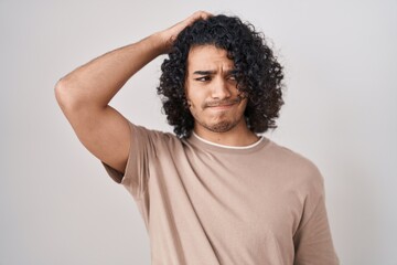 Hispanic man with curly hair standing over white background confuse and wondering about question....