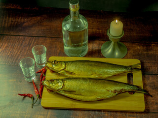 Still life in antique style with fish and alcohol on a wooden table. - 688211869