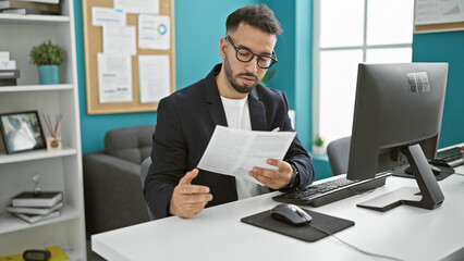 Young arab man business worker using computer reading document at the office