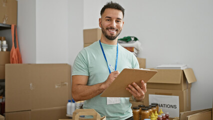 Young arab man volunteer taking notes smiling at charity center