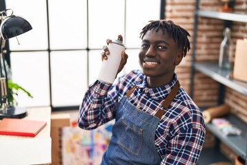 African american man artist smiling confident holding graffiti spray at art studio