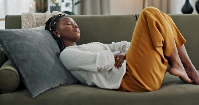 Woman, stomach and sick of pain on sofa for gut health, indigestion and gastric virus in lounge. African girl with ibs, menstruation and constipation of abdomen, endometriosis or bad bloating at home