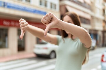 Young beautiful woman doing negative sign with thumbs down at street