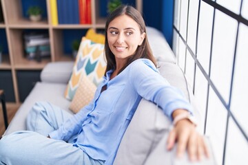Young beautiful hispanic woman smiling confident sitting on sofa at home