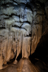 Amazing view of stalactites and stalagmites in colourful bright light, beautiful natural landmark in touristic place. - obrazy, fototapety, plakaty
