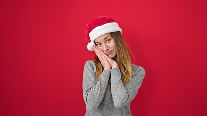 Young caucasian woman smiling confident wearing christmas hat over isolated red background