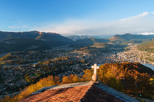 Wide-angle sunset view from the summit of Monte San Salvatore overlooking Lake Lugano Breathtaking panorama of the city, Melide causeway and the Swiss Alps in Ticino, Switzerland - November 2023