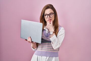 Young caucasian woman working using computer laptop thinking worried about a question, concerned and nervous with hand on chin