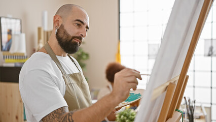 Two artists, a man and a woman, wear aprons in an indoor studio, concentrating on drawing together...
