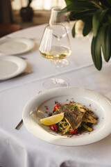 Appetizing fried piece of fish fillet with grilled vegetables and lemon. Restaurant, banquet, buffet.