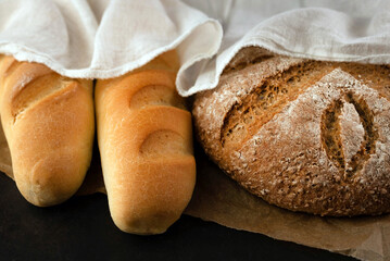Freshly baked baguettes and rye bread on a dark background. Home baking concept.