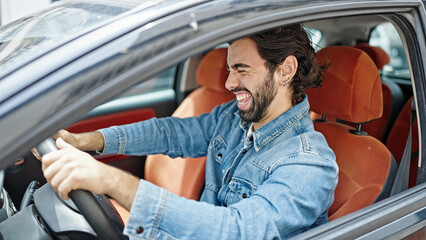 Young hispanic man smiling confident driving car at street