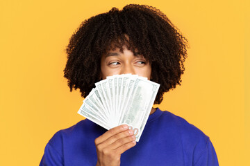 Young black man holding fan of cash over his face