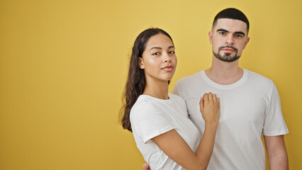 Obraz premium Beautiful couple sporting serious faces on an isolated yellow background, the face of modern love and relationships
