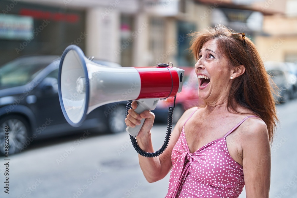 Poster Middle age woman using megaphone screaming at street