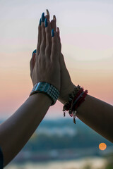 Close up view of female hands clapping outdoors during sunset near the river. Give me five