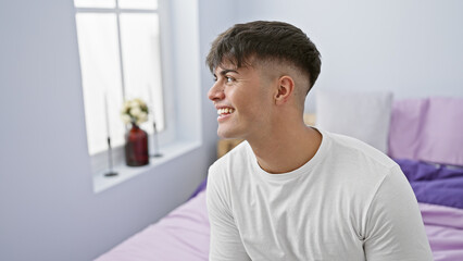 Handsome young hispanic man confidently enjoying a relaxing morning, sitting happily on a cozy bed...
