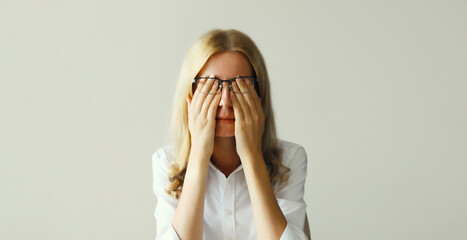 Tired overworked young woman rubbing her eyes suffering from eye strain, dry eye syndrome or...