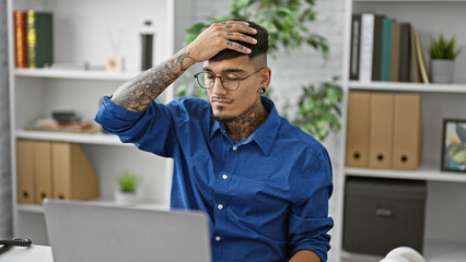 Stressed young latin business worker, man sweating bullets overwork using laptop at office desk.