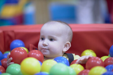 Obraz premium a one-year-old child, a boy, a joyful kid in toys, a lot of balls