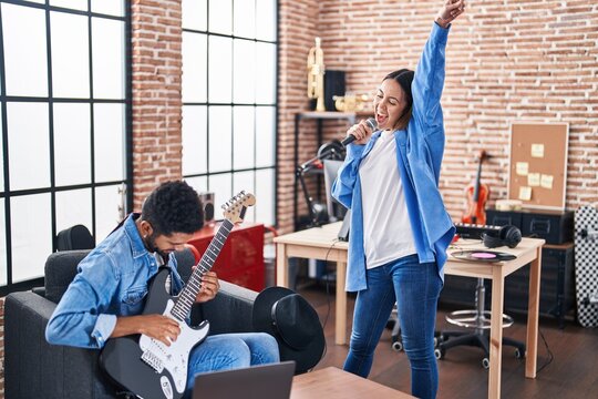 Man and woman musicians singing song playing electrical guitar at music studio