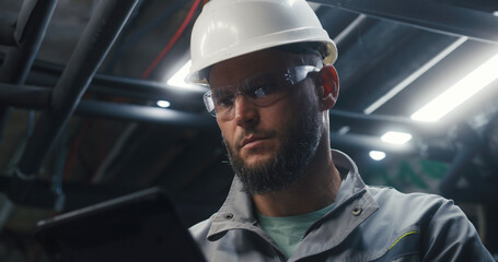 Close up of professional Caucasian engineer using digital tablet computer on industrial...