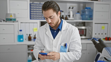 Young hispanic man scientist using smartphone at laboratory