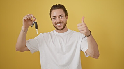 Young hispanic man holding key of new car doing thumb up gesture over isolated yellow background
