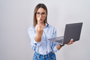 Young woman working using computer laptop showing middle finger, impolite and rude fuck off...
