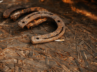 Rusty metal horse shoe on a dirty wooden surface. Symbol of luck.