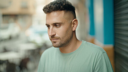 Young hispanic man looking to the side with serious expression at street