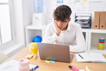 Young hispanic teenager business worker stressed using laptop at office