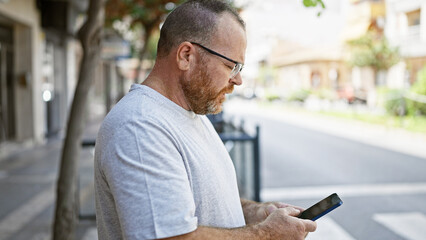 Caucasian man using smartphone with serious expression at street