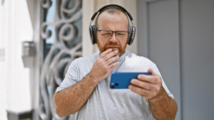 Caucasian man using smartphone wearing headphones at street